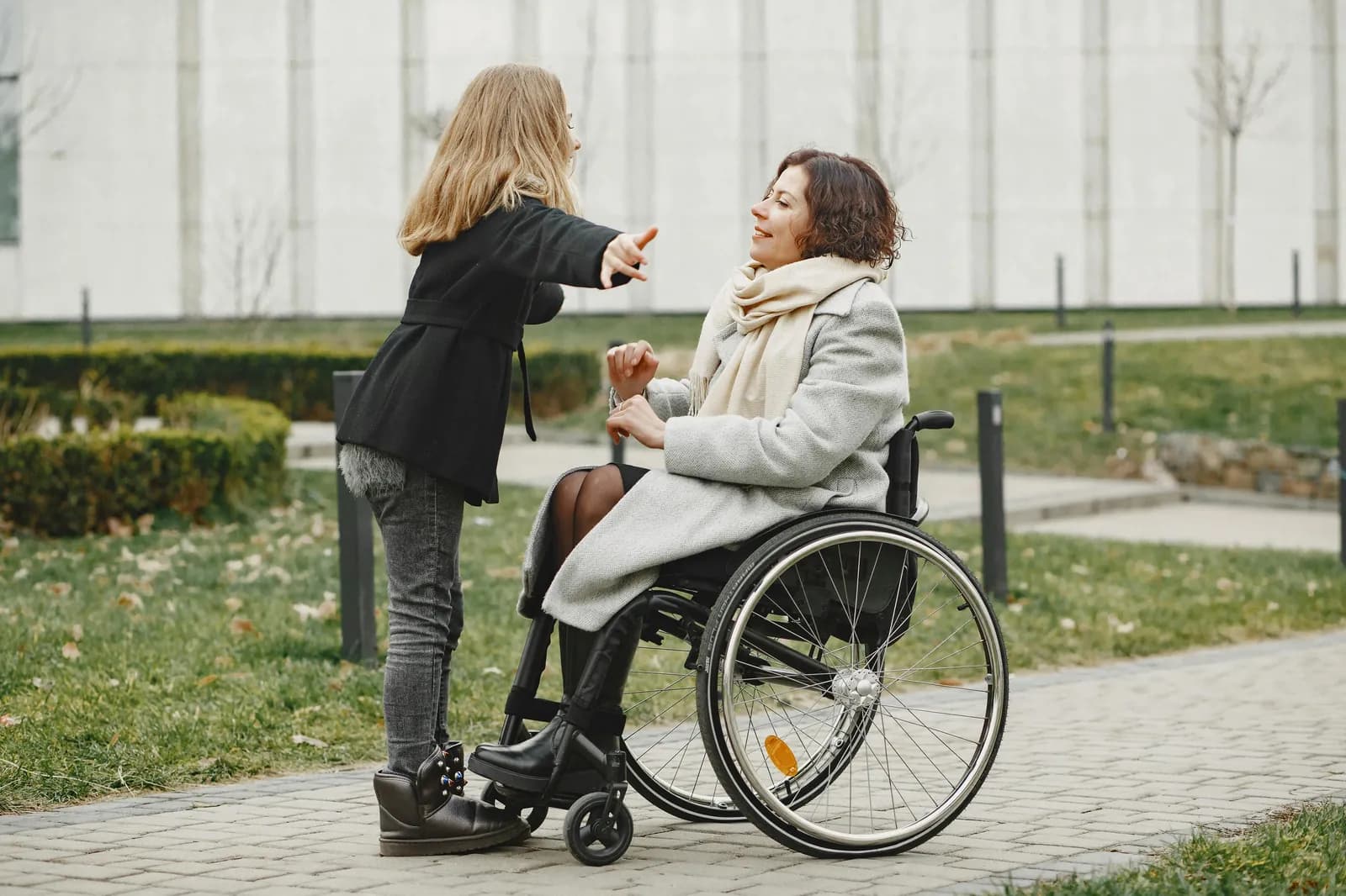 A woman using a wheelchair talking with a companion outdoors while navigating the Indiana Medicaid and SFC approval process