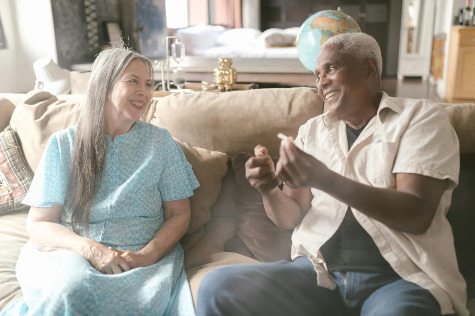 An older couple talking together on a couch at home as one explains something, weighing a caregiver agency decision in Indiana