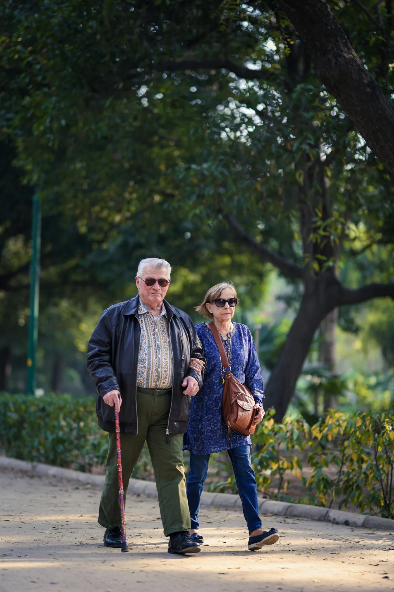 An adult child and elderly parent sitting close together on a porch at home, at ease