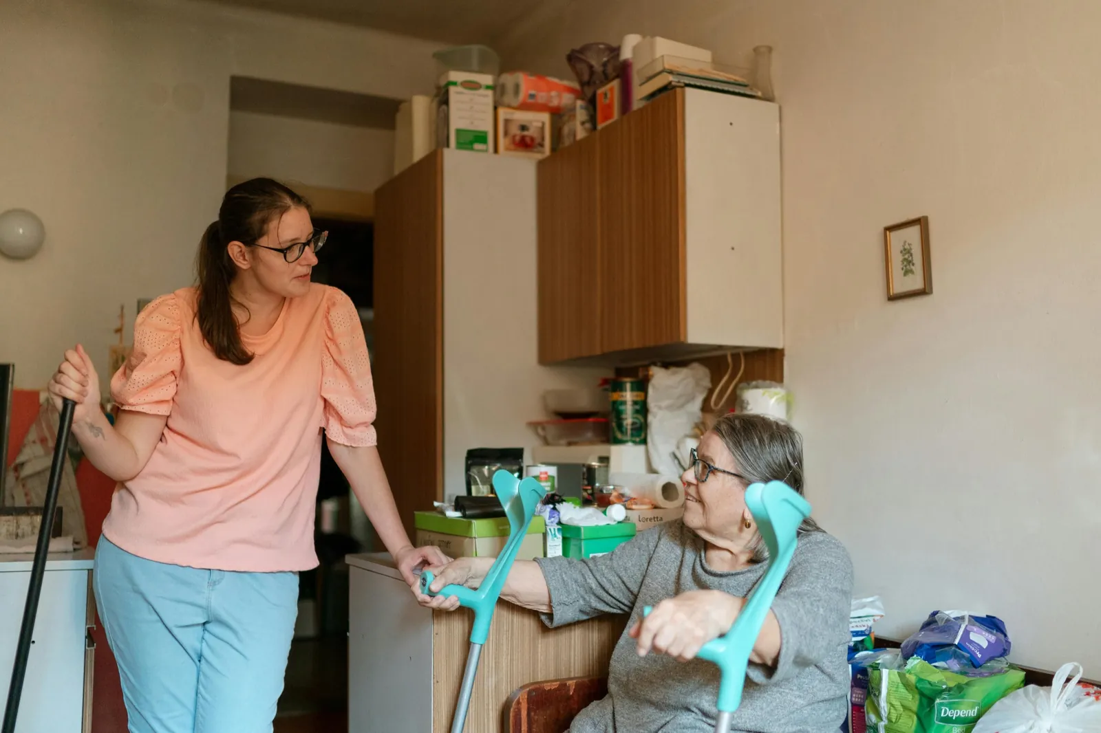 An adult child sitting with an aging parent at home, talking gently over coffee