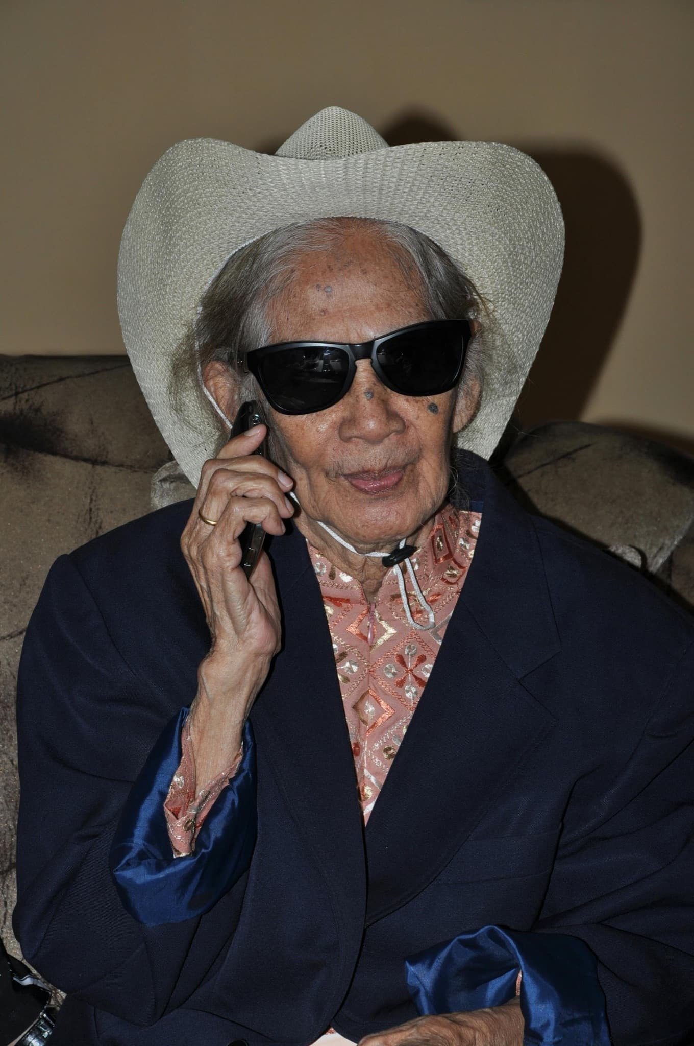 Margaret, an older woman in a cowboy hat and sunglasses, on the phone