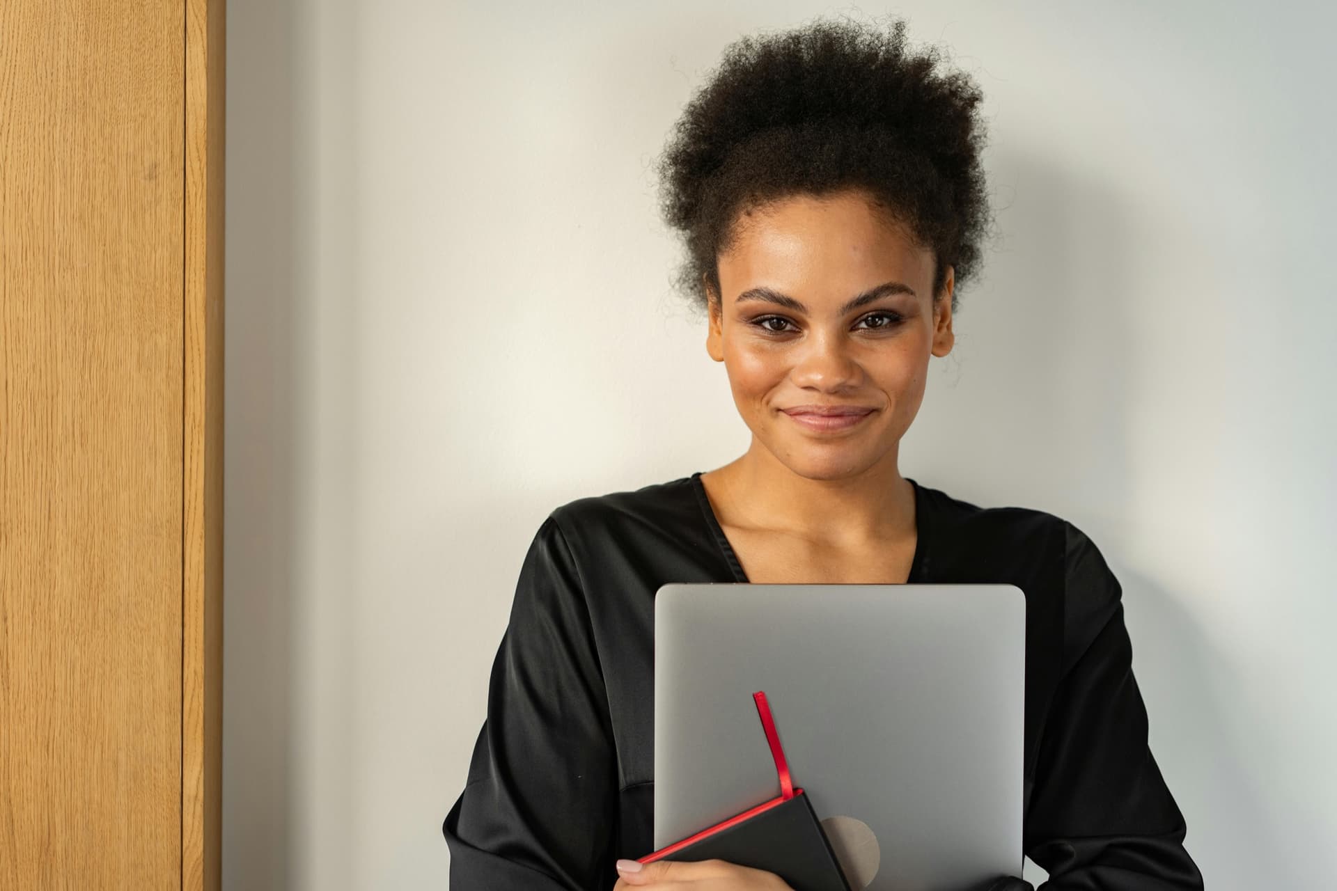 Carla, a young Black woman with a laptop, smiling