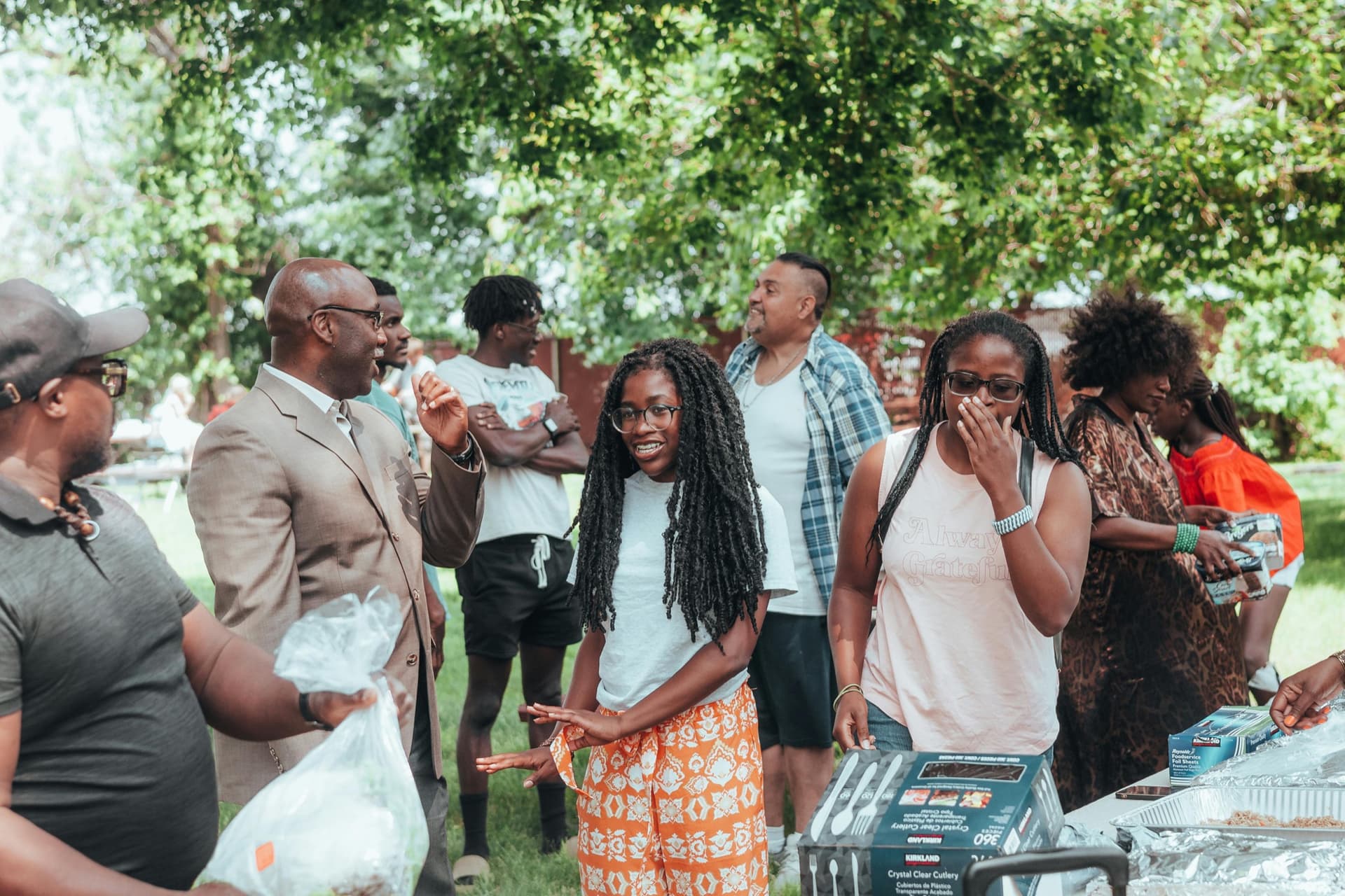 Three women and a child smiling outdoors at a community gathering