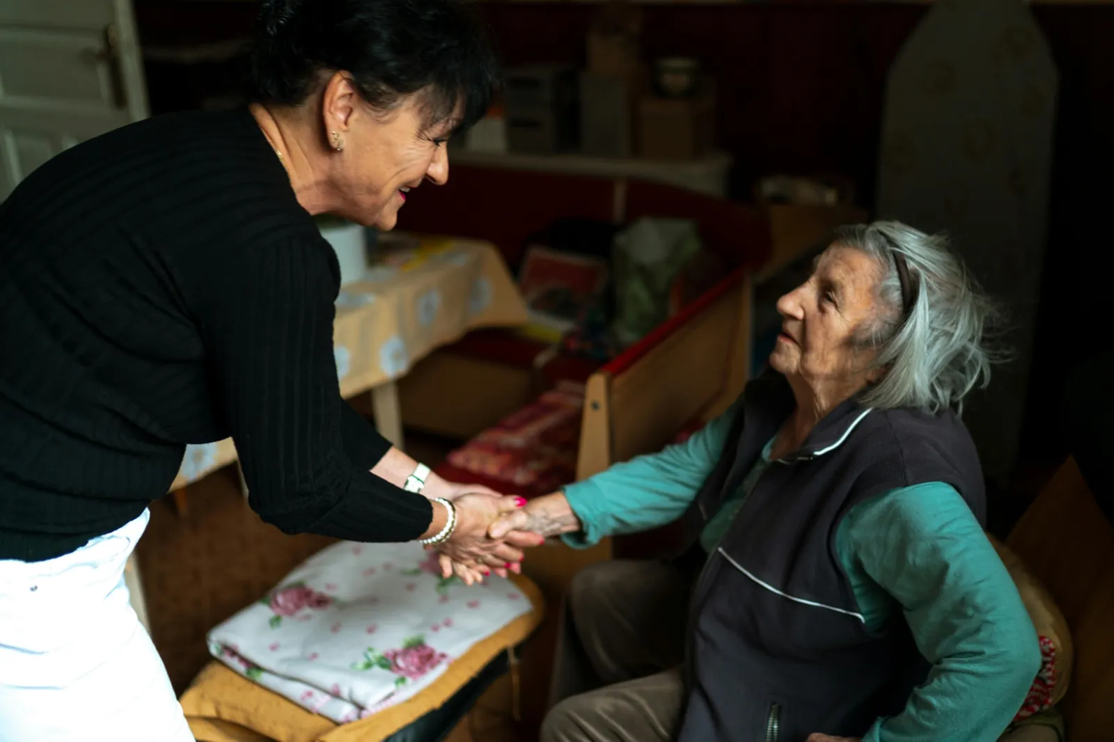 An adult child gently holding the hands of an elderly parent with dementia at home